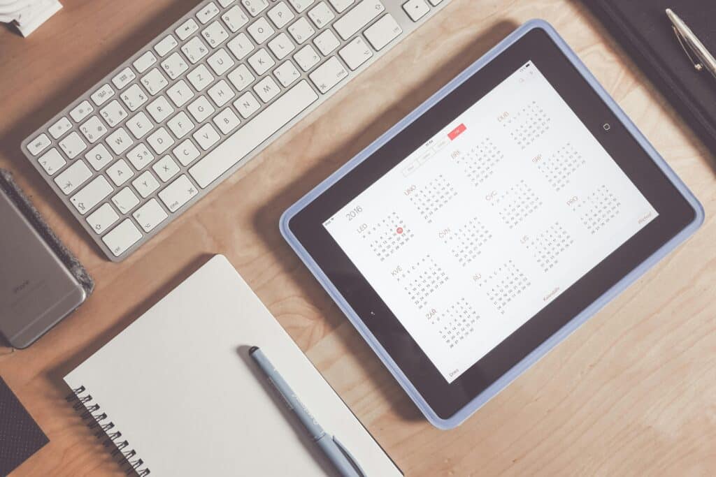 Une tablette avec un agenda est posée, bien alignée avec un clavier, un bloc notes, etc
