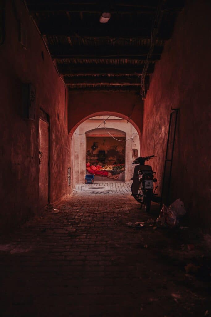 Ruelle étroite avec une moto - Une Autre Voix Ruelle étroite avec une moto dans les tons rouges