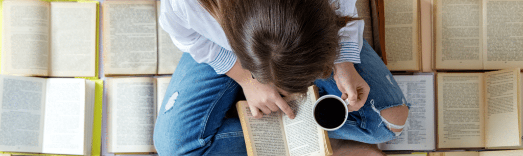 Une femme lit un livre avec un café dans la main